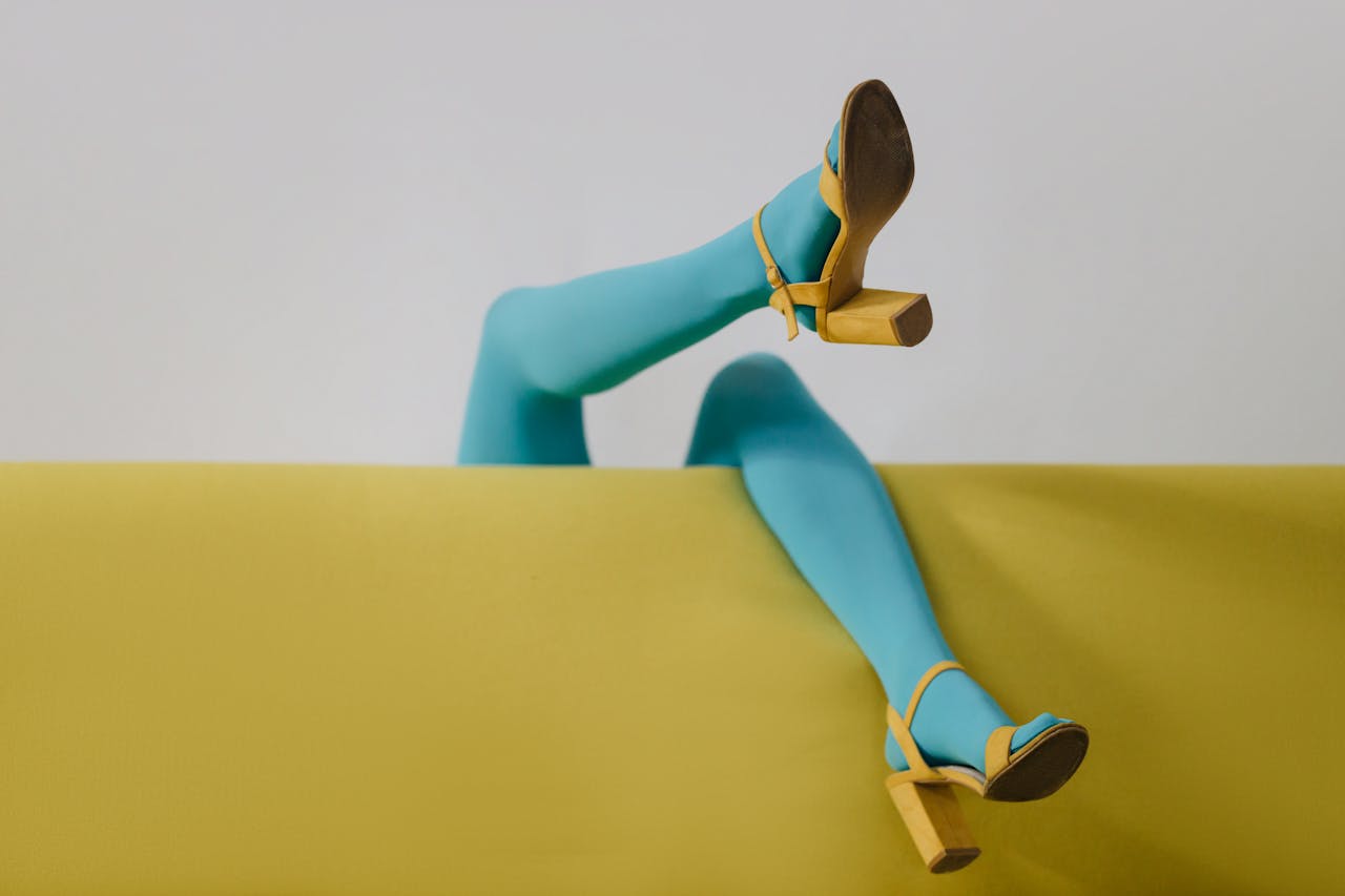 about-img-01 Stylized image featuring vibrant blue tights and yellow heels on a minimalist sofa.